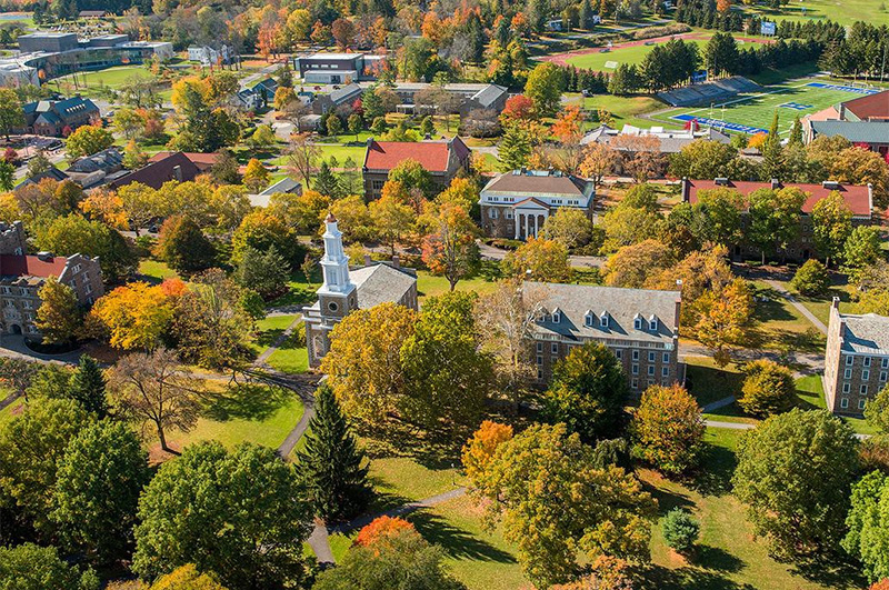 Aerial view of private college campus with many buildings and fall foliage.